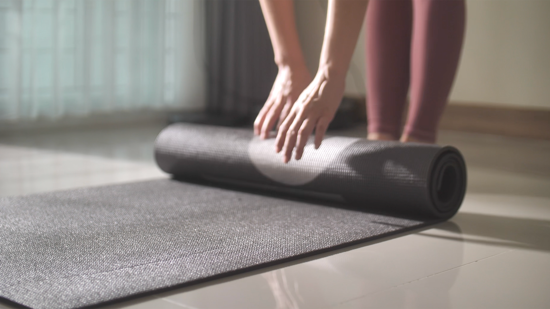 Student Rolling out a yoga mat, getting ready for class.