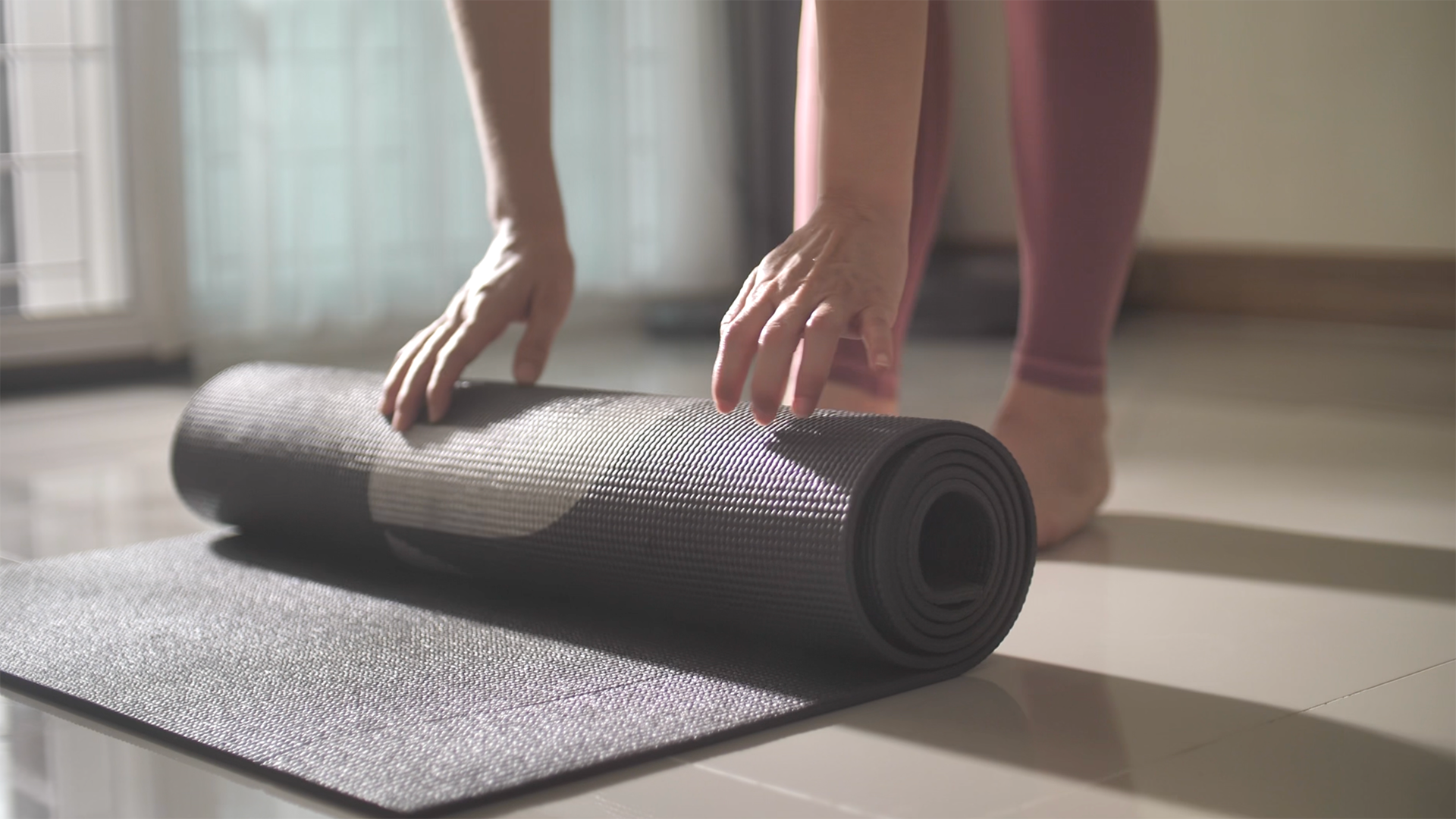 Student Rolling out a yoga mat, getting ready for class.